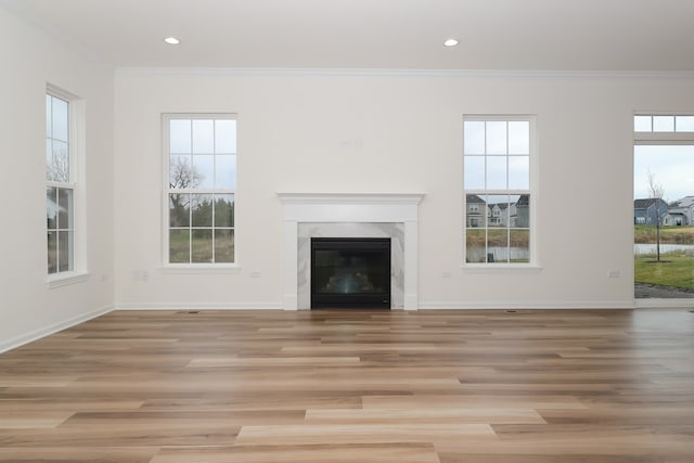 unfurnished living room featuring plenty of natural light, light wood-type flooring, and crown molding