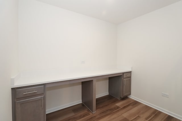 unfurnished office featuring dark hardwood / wood-style flooring and built in desk