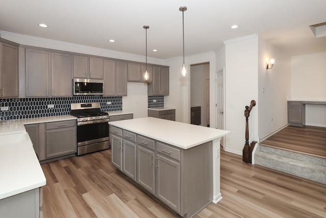 kitchen featuring appliances with stainless steel finishes, light hardwood / wood-style flooring, hanging light fixtures, and gray cabinetry