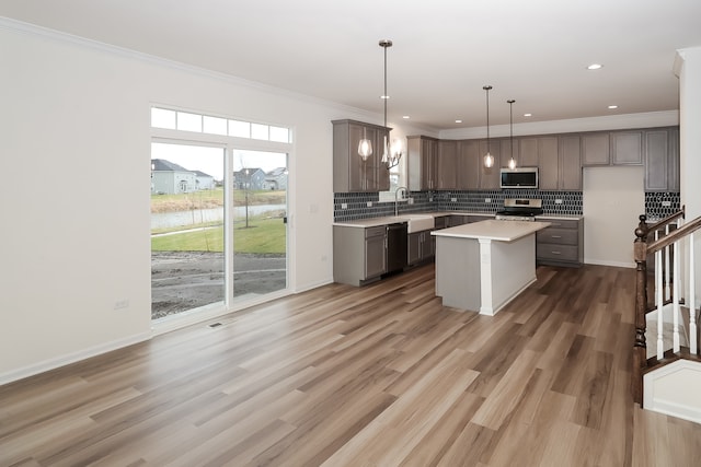 kitchen featuring a center island, wood-type flooring, hanging light fixtures, and appliances with stainless steel finishes