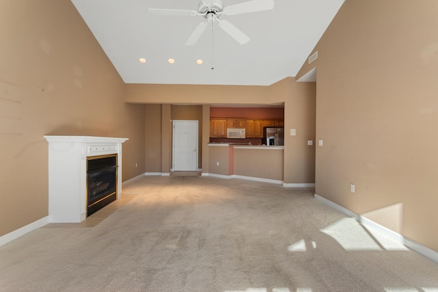 unfurnished living room featuring high vaulted ceiling, ceiling fan, a fireplace with flush hearth, visible vents, and light carpet