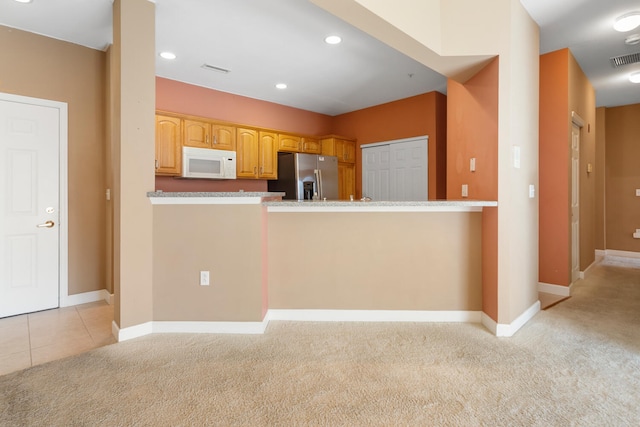kitchen with light carpet, white microwave, baseboards, and stainless steel fridge