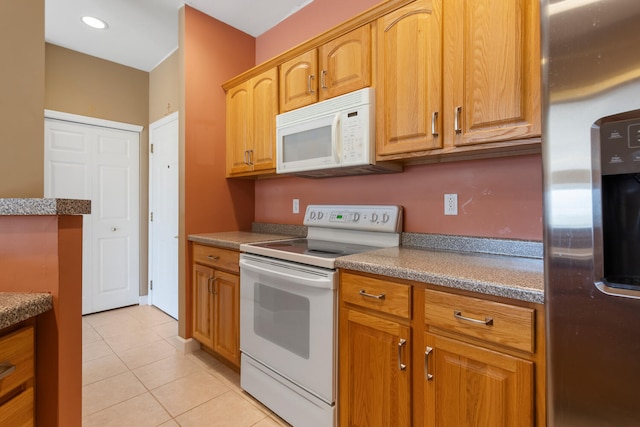 kitchen with brown cabinets, light tile patterned floors, and white appliances