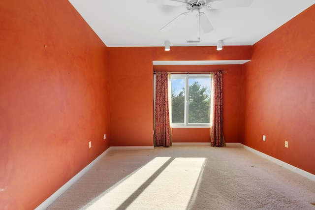 carpeted spare room featuring visible vents, baseboards, and a ceiling fan