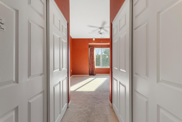 hall featuring light colored carpet and baseboards