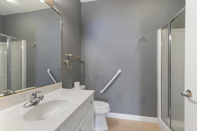 bathroom with baseboards, toilet, vanity, tile patterned flooring, and a stall shower