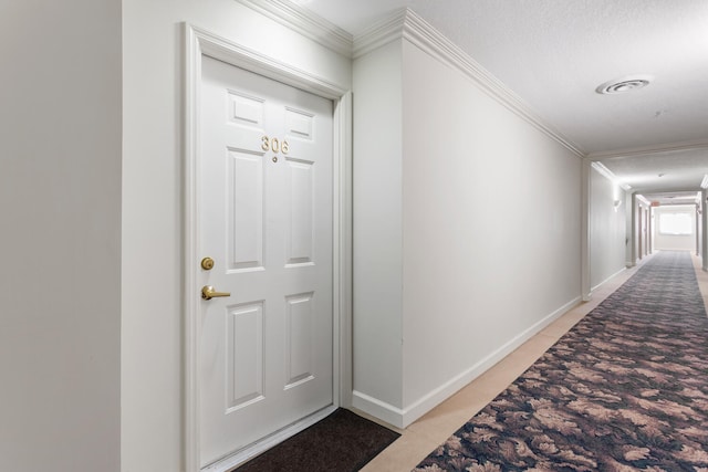hall featuring visible vents, baseboards, ornamental molding, and light tile patterned flooring