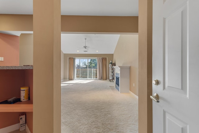 hallway with carpet, baseboards, and lofted ceiling