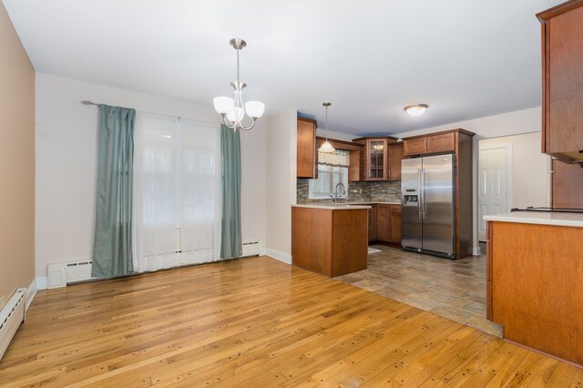 kitchen featuring kitchen peninsula, stainless steel refrigerator with ice dispenser, baseboard heating, light hardwood / wood-style floors, and hanging light fixtures