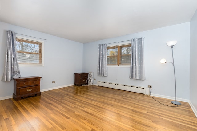 unfurnished room with light wood-type flooring, a baseboard radiator, and a wealth of natural light