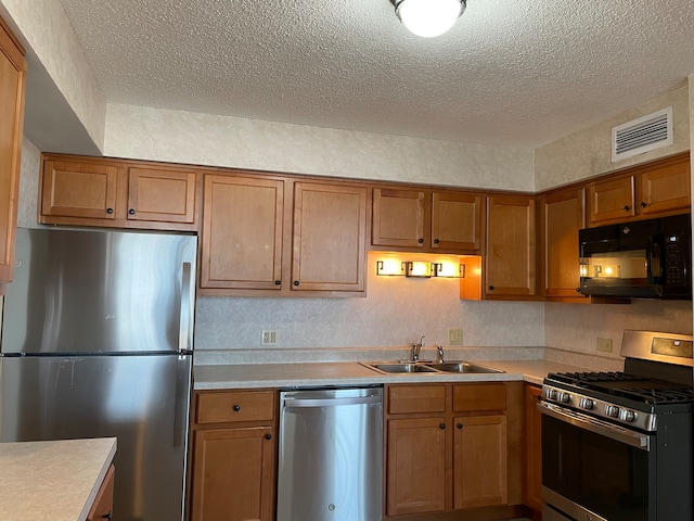 kitchen with sink, a textured ceiling, and appliances with stainless steel finishes