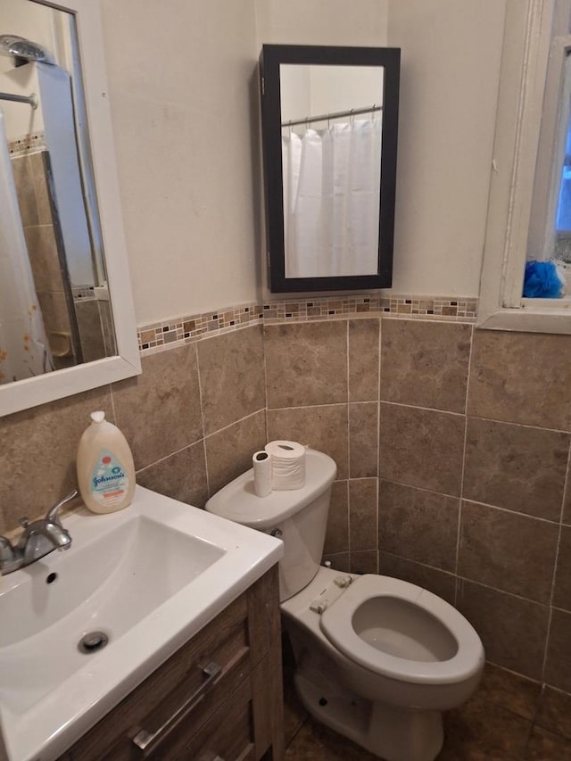 bathroom featuring vanity, toilet, tile walls, and curtained shower