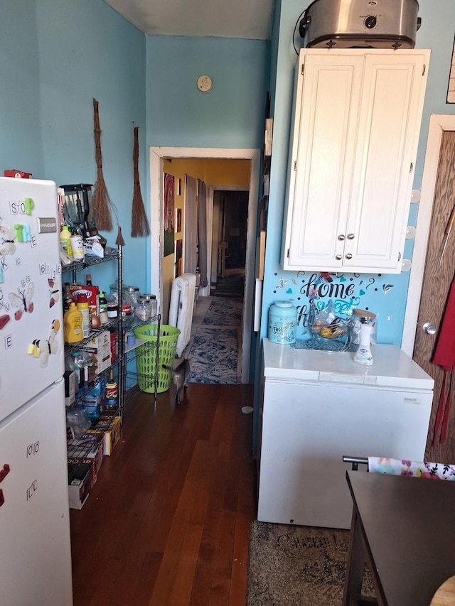 kitchen with white cabinets, white fridge, and dark wood-type flooring