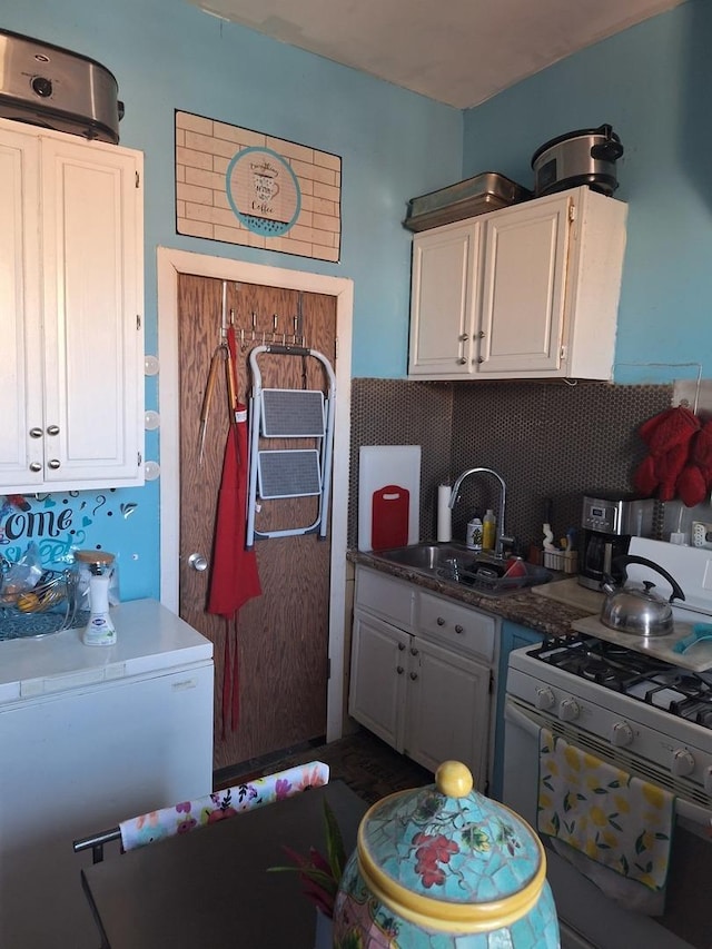 kitchen with white cabinetry, white gas stove, sink, tasteful backsplash, and fridge