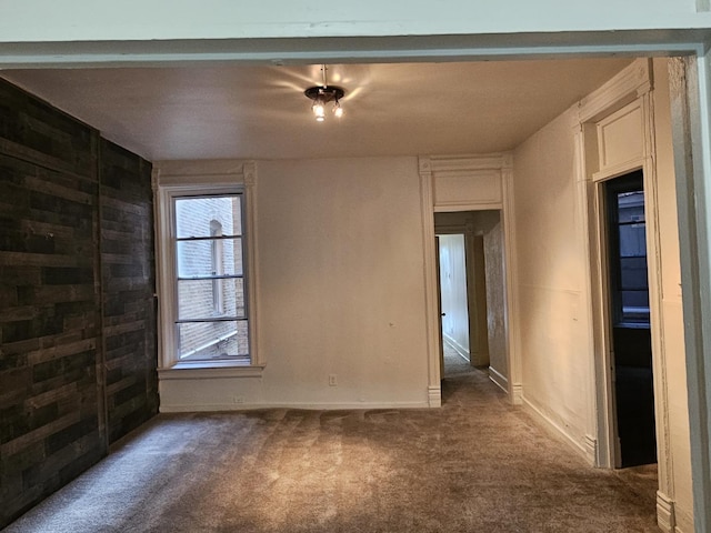 unfurnished room featuring dark colored carpet and wooden walls