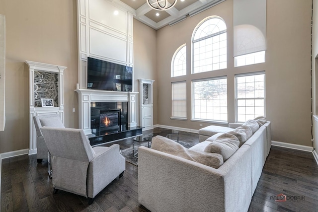 living area with dark wood finished floors, coffered ceiling, baseboards, and a towering ceiling