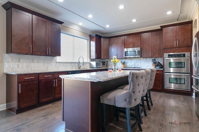 kitchen with dark wood-type flooring, backsplash, appliances with stainless steel finishes, and a center island