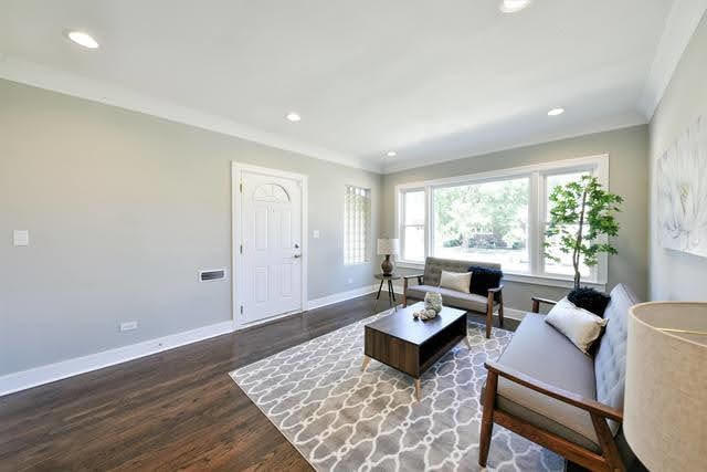 living room featuring dark wood-type flooring and ornamental molding