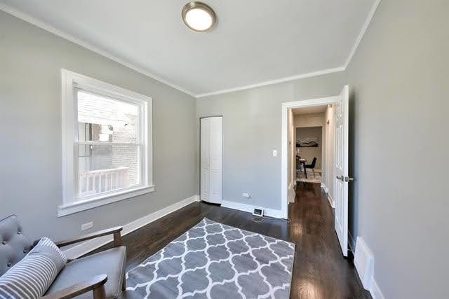 living area featuring crown molding and dark wood-type flooring