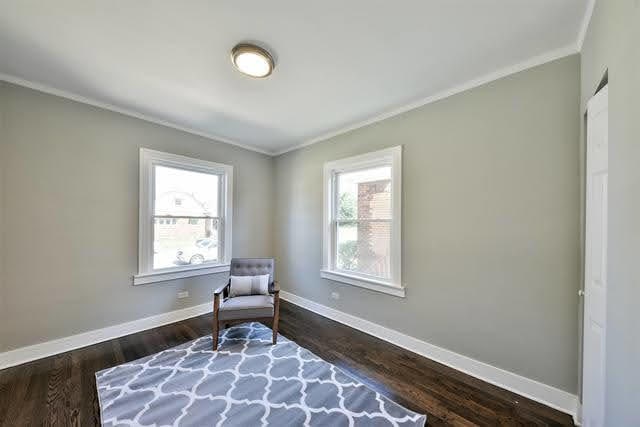 living area featuring a wealth of natural light, dark hardwood / wood-style flooring, and ornamental molding