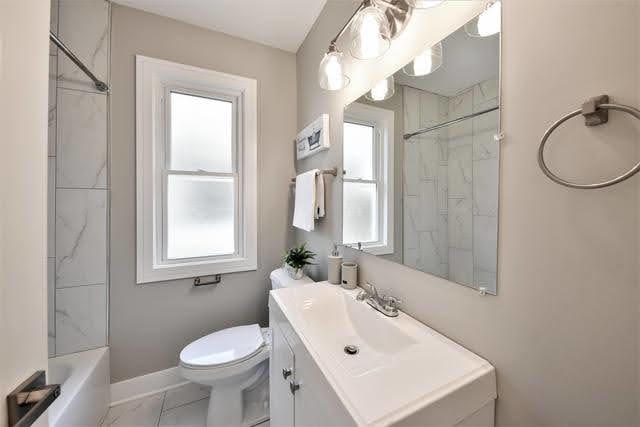 full bathroom featuring tile patterned floors, vanity, tiled shower / bath combo, and toilet