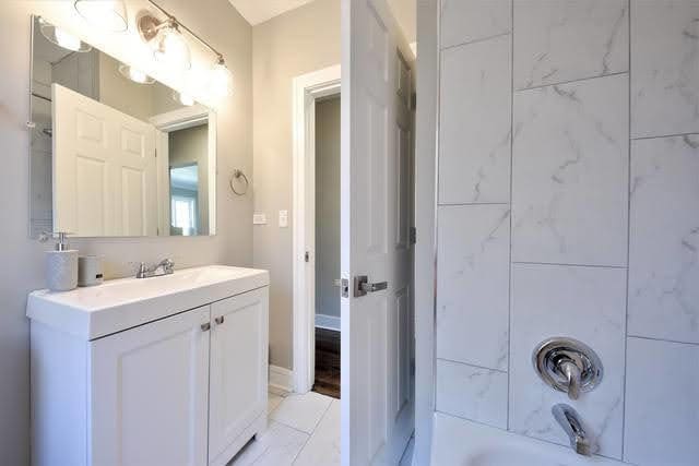 bathroom featuring tiled shower / bath combo and vanity