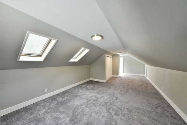 bonus room featuring vaulted ceiling with skylight and carpet floors