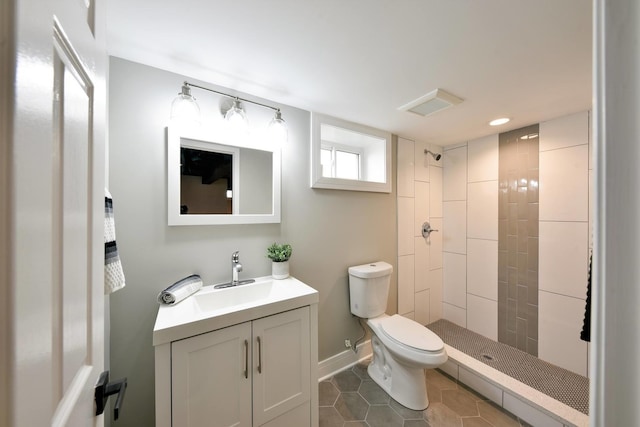 bathroom with tile patterned floors, vanity, a tile shower, and toilet