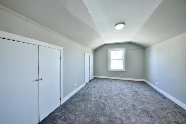 bonus room with dark colored carpet and vaulted ceiling