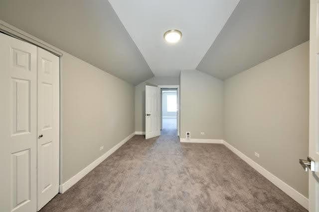 additional living space with light colored carpet and vaulted ceiling