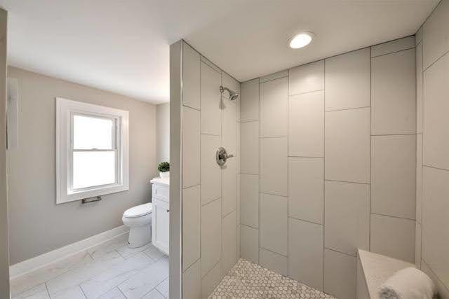 bathroom with a tile shower and toilet