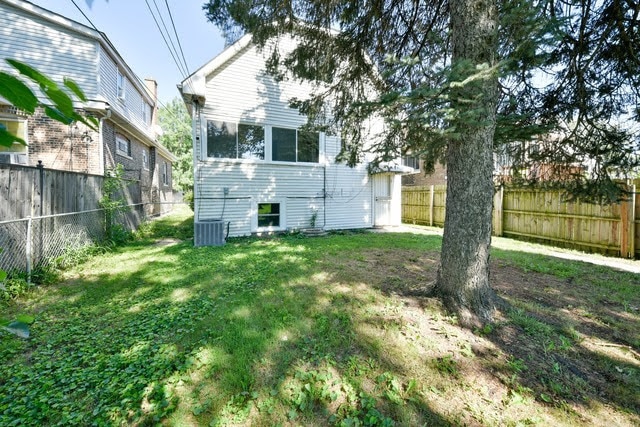 rear view of house featuring central AC and a yard