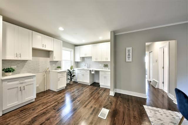 kitchen featuring white cabinets, dark hardwood / wood-style floors, tasteful backsplash, and ornamental molding