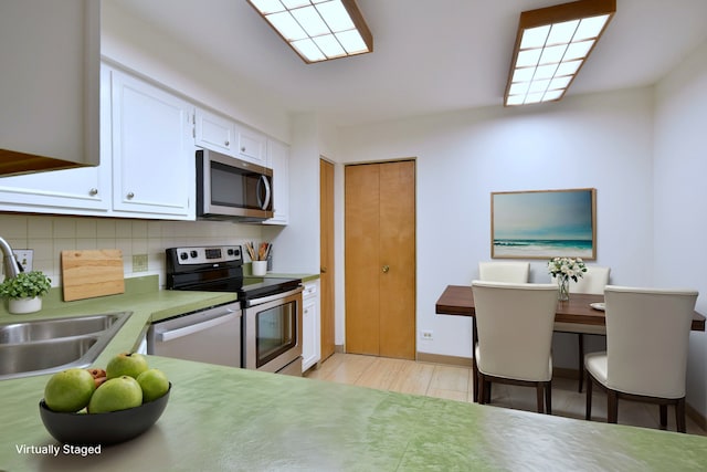 kitchen featuring tasteful backsplash, sink, stainless steel appliances, and white cabinets