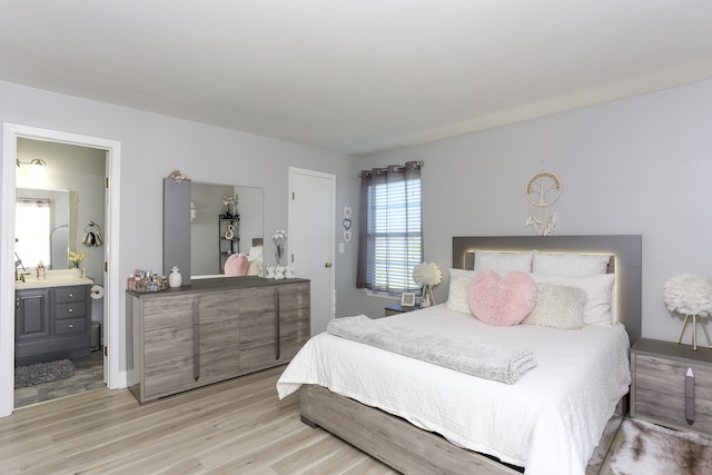 bedroom with ensuite bathroom and light hardwood / wood-style flooring