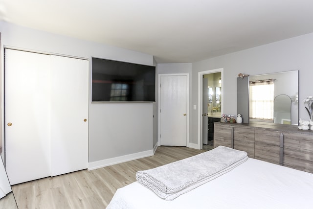 bedroom with light hardwood / wood-style floors and ensuite bath