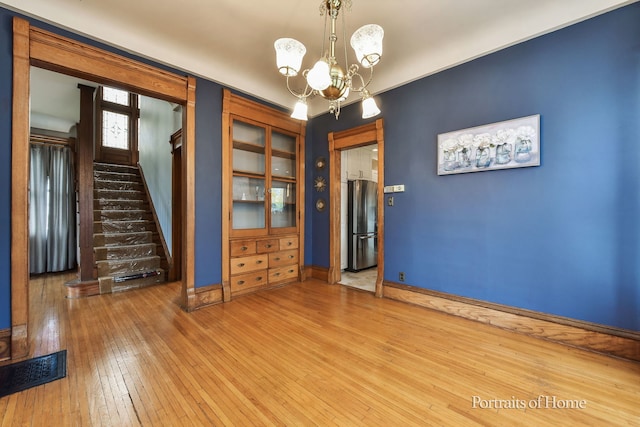 unfurnished room featuring wood-type flooring and a chandelier