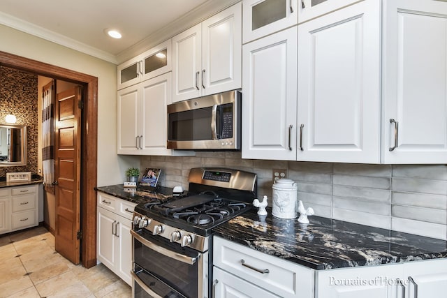 kitchen featuring decorative backsplash, dark stone countertops, white cabinetry, and stainless steel appliances