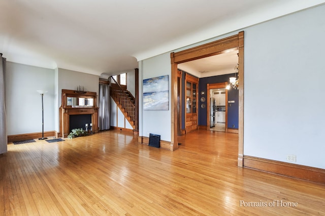 unfurnished living room with a chandelier and hardwood / wood-style flooring