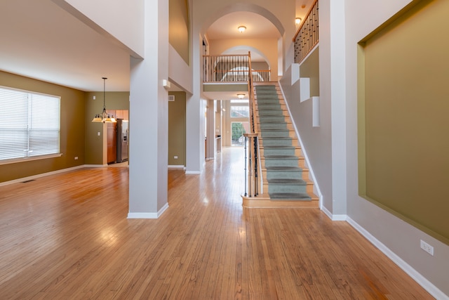 entryway with a towering ceiling, an inviting chandelier, and light hardwood / wood-style flooring