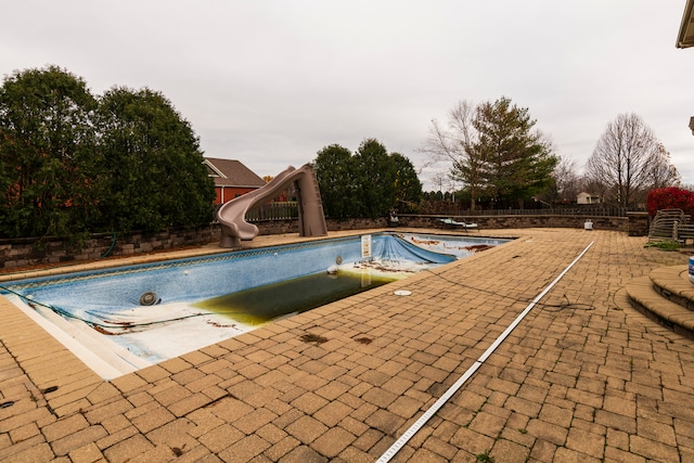 view of swimming pool featuring a water slide and a patio