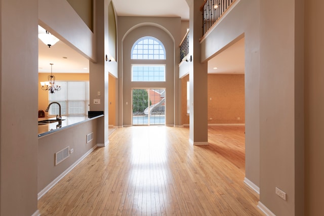 foyer entrance featuring a high ceiling, an inviting chandelier, light hardwood / wood-style flooring, and sink