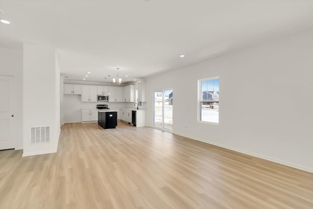 unfurnished living room featuring light wood-type flooring, visible vents, baseboards, and recessed lighting