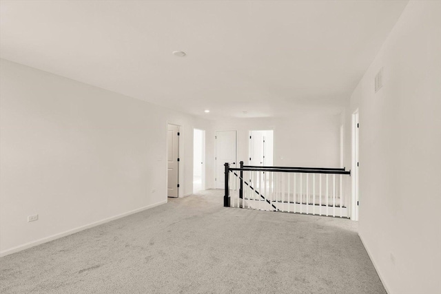 empty room with baseboards, visible vents, and light colored carpet