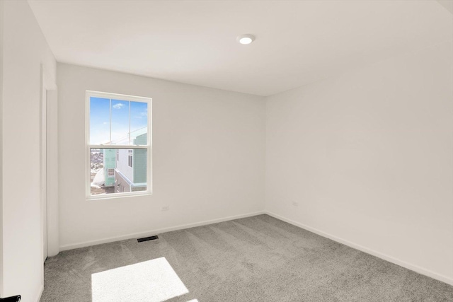 spare room featuring carpet, visible vents, and baseboards