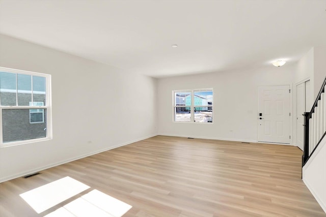 interior space with light wood-type flooring, visible vents, stairway, and baseboards