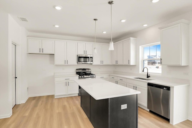 kitchen with white cabinets, a kitchen island, appliances with stainless steel finishes, decorative light fixtures, and light countertops