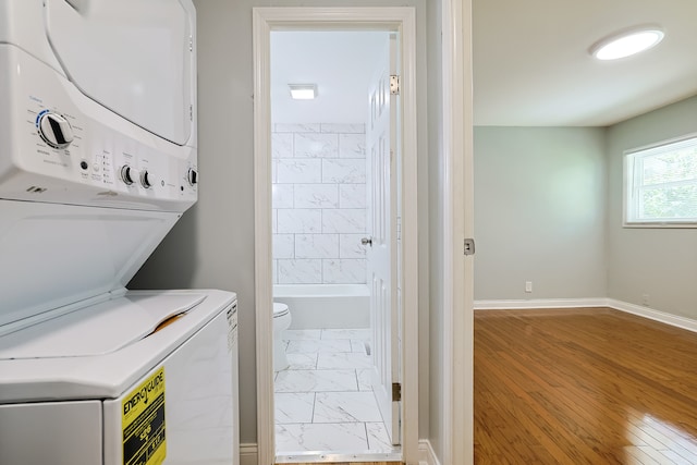 laundry area with hardwood / wood-style flooring and stacked washer and clothes dryer