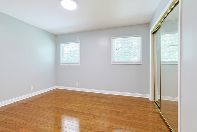 unfurnished bedroom featuring multiple windows, a closet, and light hardwood / wood-style flooring