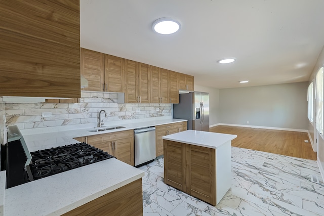 kitchen with sink, light hardwood / wood-style flooring, backsplash, a kitchen island, and appliances with stainless steel finishes